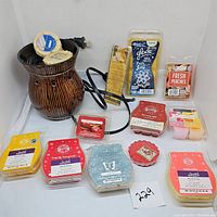 Photo of brown striped ceramic electric wax warmer with electrical cord and a variety of wax melts in packaging including Scentsy and Glade brands.