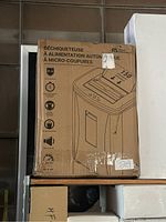 Photo of the Royal Sovereign shredder box front with technical features listed in French, showing it is an auto-feed, micro-cut machine with a capacity of 150 sheets.