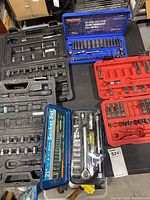 Overview photo showing all five socket wrench sets arranged on a surface, displaying varying amounts of sockets and tools inside each case.