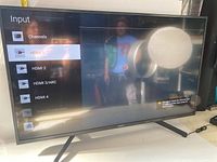 Front view of the Sony 42 inch TV powered on displaying the input source menu.