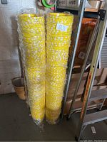 Two tall stacks of yellow plastic popcorn buckets wrapped in plastic containing popcorn graphics.