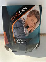 Front side of damaged retail packaging of Relax Eden weighted blanket showing a child sleeping.