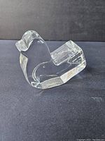 Clear glass bird-shaped paperweight shown from front and side angles on black background.