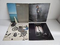 Front view of 4 vinyl record covers: Pat Metheny Watercolors with visible damage, Robert Cray Strong Persuader, Stanley Clarke Rocks Pebbles and Sand, and another Stanley Clarke album