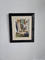 Framed painting hanging on a white wall showing colorful abstract shapes in the style of Joan Miró.