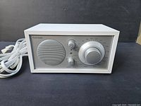 Front and power cord view of Tivoli Audio Model One radio showing speaker, control knobs, and labeling.