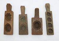 Front view of 4 wooden butter or candy moulds showing carved designs.