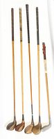 Full view of five antique golf clubs of assorted lengths showing shafts and club heads