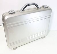 Closed matte silver metal briefcase showing front side with handle and lock clasps.