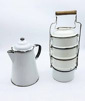 Photo of white enamel coffee pot with black handle and 5-section metal lunch stack with wooden carry handle