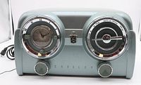 Front view of silver blue Crosley radio showing clock, speaker, controls and brand name