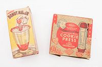 Both original boxes for the Popeil Bros Donut Maker and Wecolite See-it Cookie Press, showing retro packaging with kitchen-themed graphics.