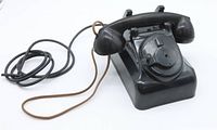 Angle view of black vintage Leich telephone with wires, showing overall shape, body and receiver, no dial.