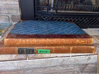 Photo of two old books stacked showing leather spines and blue marbled cover on one