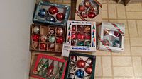 Full view of multiple boxed and loose vintage Christmas ornaments packed on floor corner