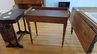 Full view of the antique wood desk/table with four turned legs and a raised back edge.