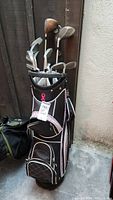 Right handed golf clubs set in black and pink golf bag, showing collection of irons and woods.