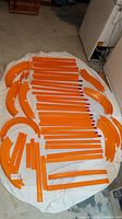 Full view of Hot Wheels orange track pieces including straight, curved pieces and loop base.