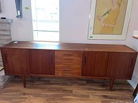 Front view of Troeds teak sideboard showing five center drawers and sliding doors at each end