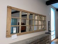 Full view of rectangular wood framed wall mirror mounted horizontally on the wall with 12 smaller mirror panes divided by muntins.