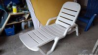 Front view of white plastic outdoor lounger with slatted seating and backrest.