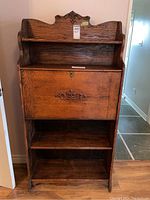 Full view of the vintage wooden secretary desk showing its upright structure with the upper shelves on top, drop-front door in the middle, and storage shelves below.