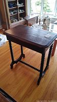 Full view of the antique dark stained wooden table on hardwood flooring, showing the top and spiral-turned legs.