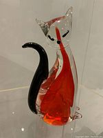 Photo showing clear orange and black glass cat figurine with stylized facial details.