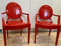 Two red Kartell Lou Lou Ghost chairs, full front view