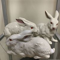 Three rabbit figurines on shelf showing overall lot