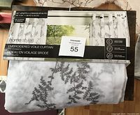 Full view of folded sheer white curtain panels with gray embroidery and packaging showing brand and size