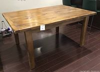 Side angle showing the rectangular pine harvest table with four legs on dark wood floor.
