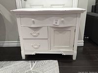 Front view of small antique painted dresser showing three drawers and one door.