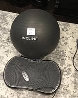 Photo of a black whole body vibration plate with a wired remote on top, next to a large black exercise ball labeled 'INCLINE'.