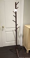 Full view of the dark wood coat stand showing its tall tree-like shape and multiple hooks.