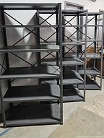 Three gray aluminum shelving units positioned side by side in a storage or warehouse setting, showing front and slight angle views.