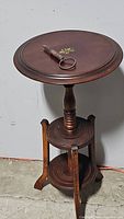 Full view of antique wooden round table showing turned central column, lower circular shelf, and three curved legs.