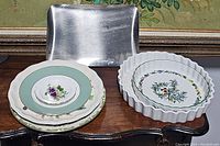 Metal rectangular baking pan and four decorative plates stacked on table