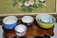 Overall assortment of mixing bowls showing various sizes and colors including vintage Pyrex bowls and floral patterned small bowls.