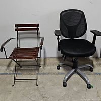 Both chairs side by side against wall on concrete floor, showing full profile of both.