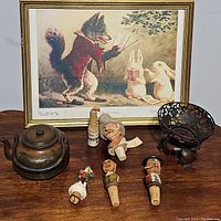 Full view of all items on wooden surface including framed print, teapot, metal bowl, and five decorative bottle stoppers.