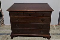 Front view of six drawer wooden dresser showing the drawer layout and metal handles.