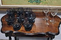 Photo showing nine smoky gray glasses and three clear glasses on a wooden table.