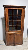 Full view of the vintage wooden china hutch showing glass upper door and wooden lower doors.