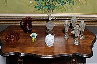 Photo showing all vintage glass and ceramic pieces on wooden table including cruets, milk glass jar, red glass jug, ashtray, and small accent pieces