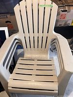 Single beige resin Adirondack chair with slatted back and armrests for outdoor use.