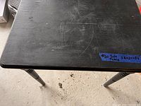 Top view of black side table surface showing visible scratches and wear.