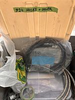 Top view of open container holding various hoses and accessories labeled 'Hoses + Other' on the lid.