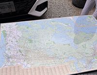 Photo showing a large map of Canada, still sealed in plastic, displaying detailed geography and road networks.