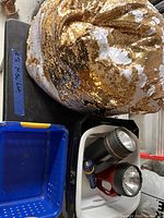 Photo showing a gold and white sequin bean bag, two flashlights (black/silver and red/black), and a small blue plastic bin.
